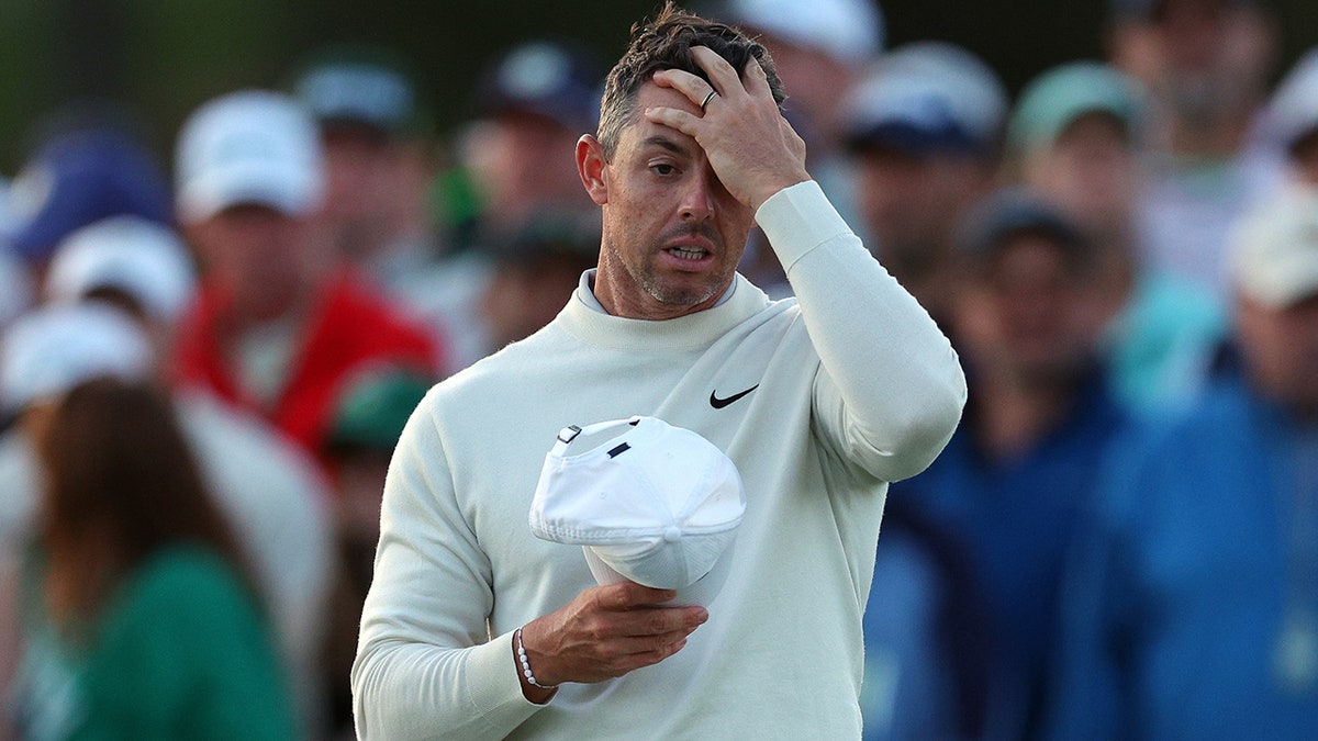 Rory McIlroy covers his head
