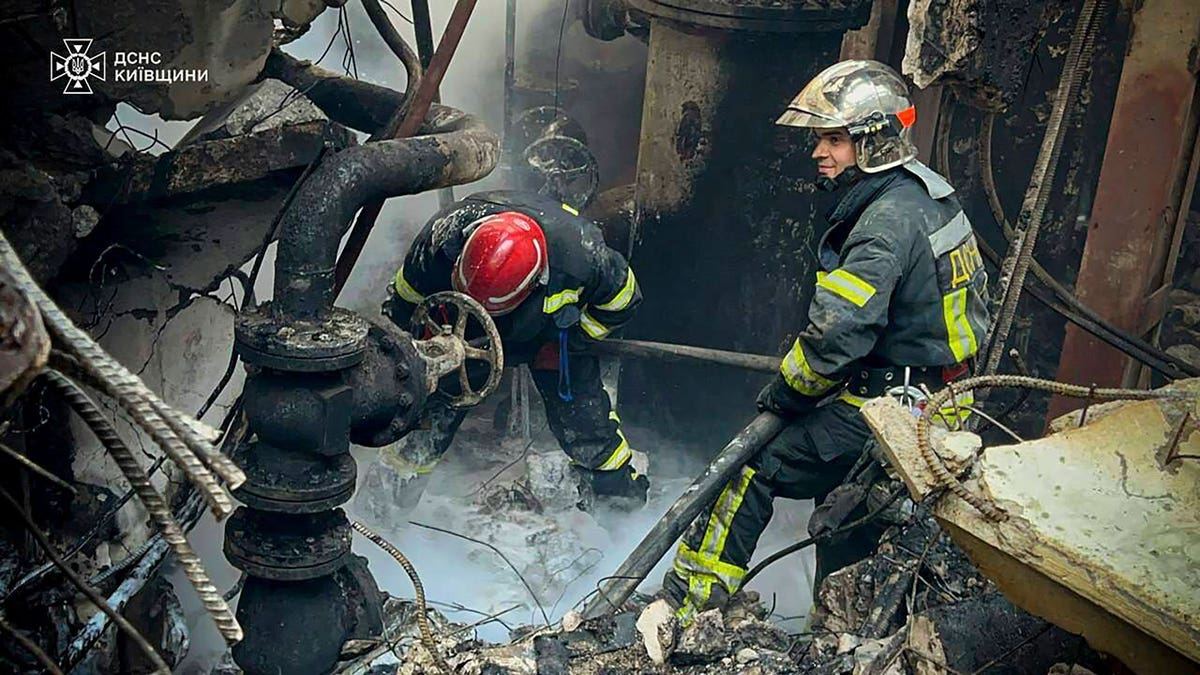 Emergency workers extinguish a fire after a Russian attack on the Trypilska thermal power plant