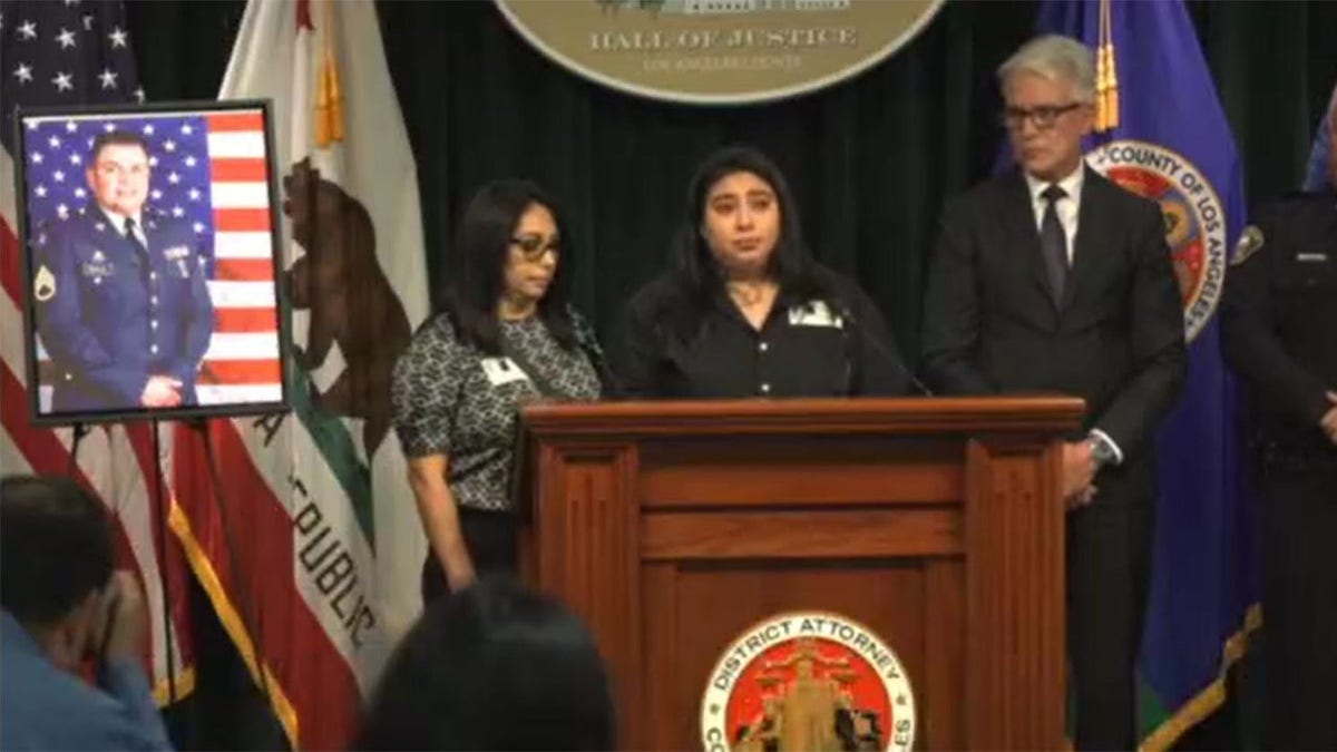 Fernanda Sandoval speaks near a photo of his father and officials standing near her