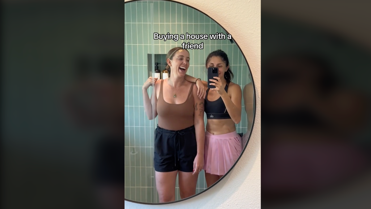 Two women take a selfie in a mirror during a TikTok video