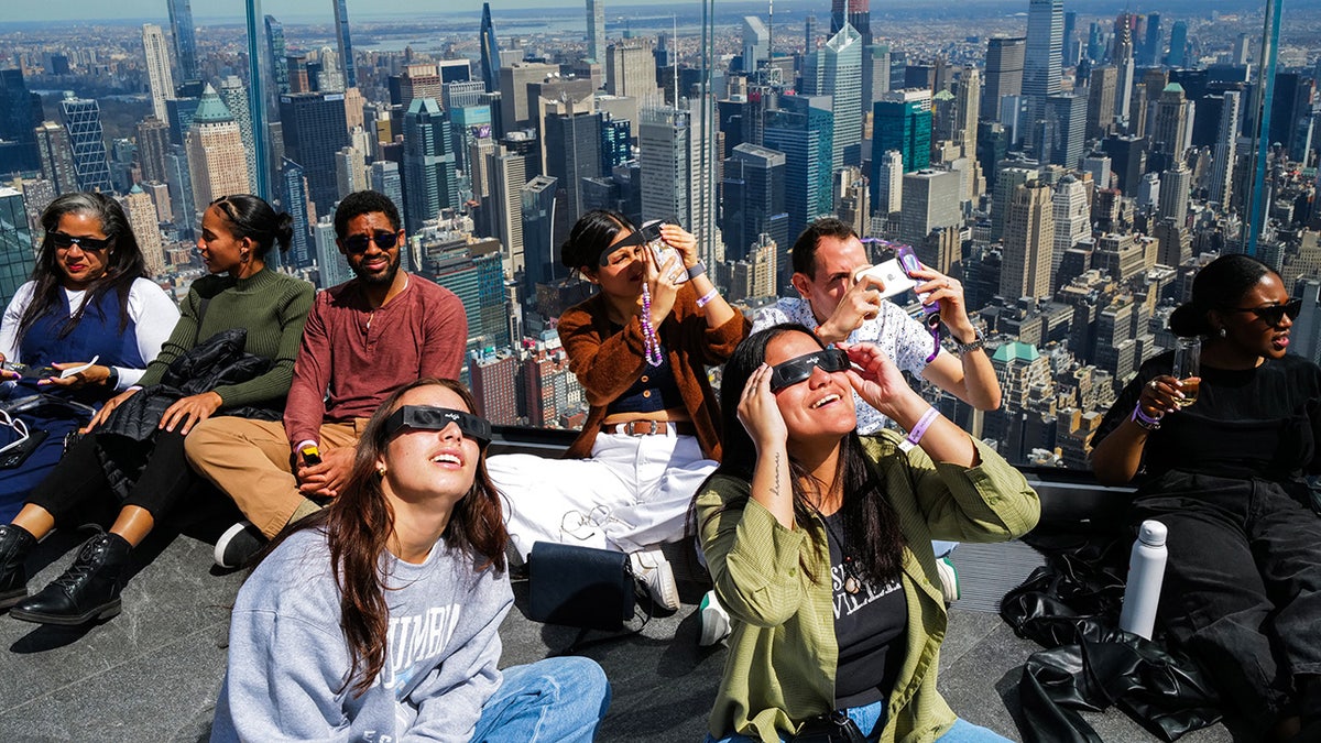 People look toward the sky at the 'Edge at Hudson Yards' observation deck ahead of a total solar eclipse