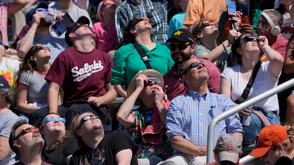 Pessoas assistem com óculos escuros enquanto a lua começa a cruzar na frente do sol durante um eclipse solar total em Carbondale, Illinois