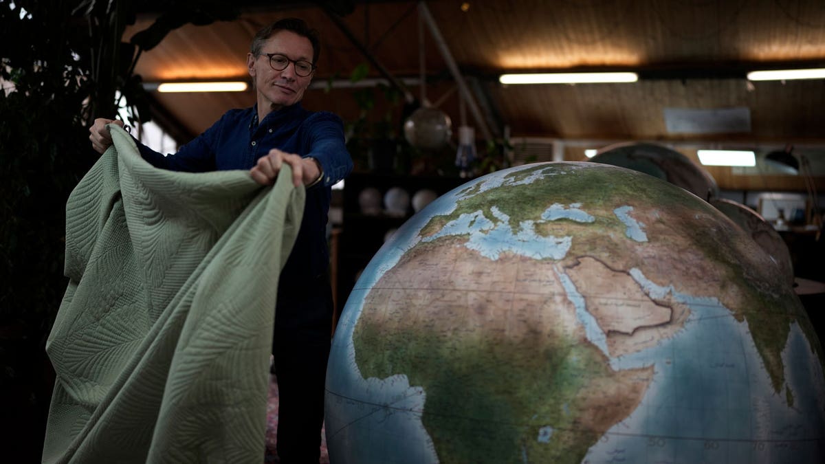 Peter Bellerby, the founder of Bellerby & Co. Globemakers, covers a globe at his studio in London