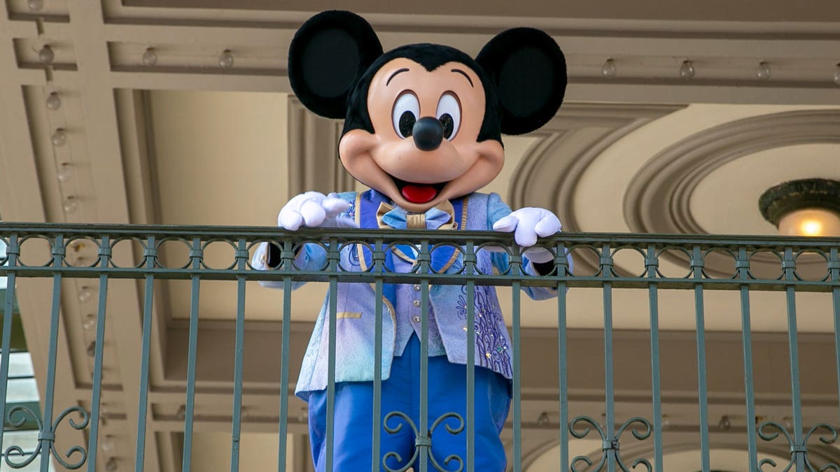 An actor dressed as Mickey Mouse greets visitors at the entrance to Magic Kingdom Park at Walt Disney World Resort