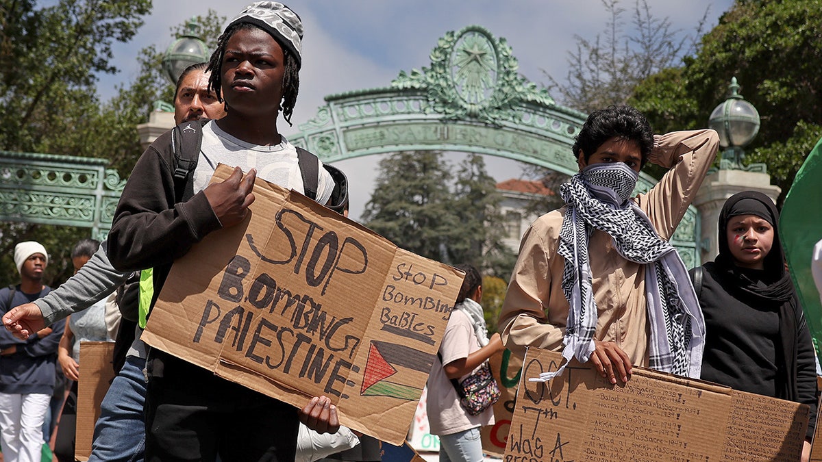 Pro-Palestinian protesters carry signs as they march in front of Sather Gate on the UC Berkeley campus