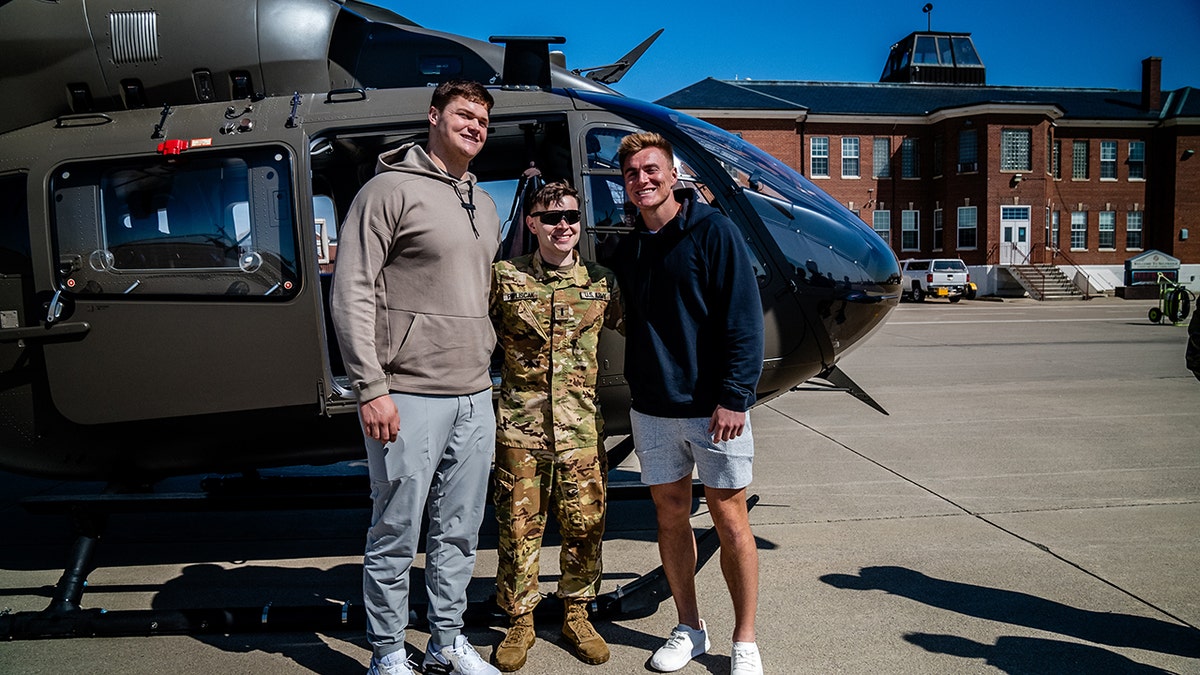 A Selfridge Air National Guard Base member poses with Joe Alt and Bo Nix in front of a helicopter