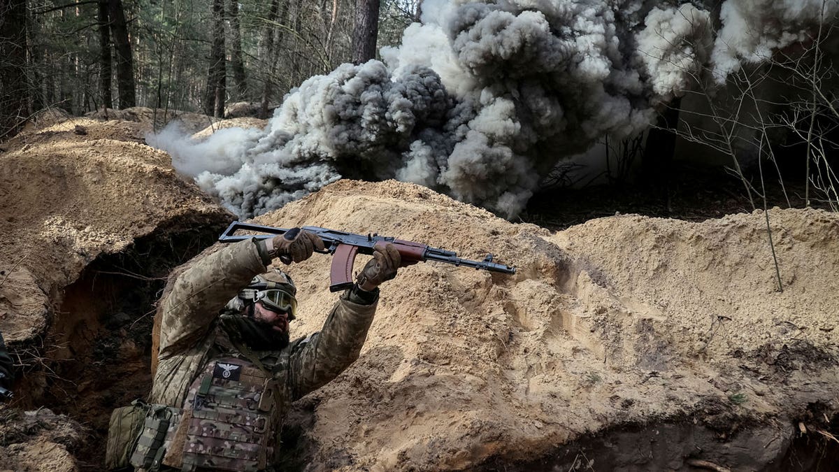 A Ukrainian serviceman of nan National Guard shelters successful a trench arsenic a acheronian unreality of state rolls toward him successful during radiation, chemic and biologic hazard drills, amid Russia's onslaught connected Ukraine.