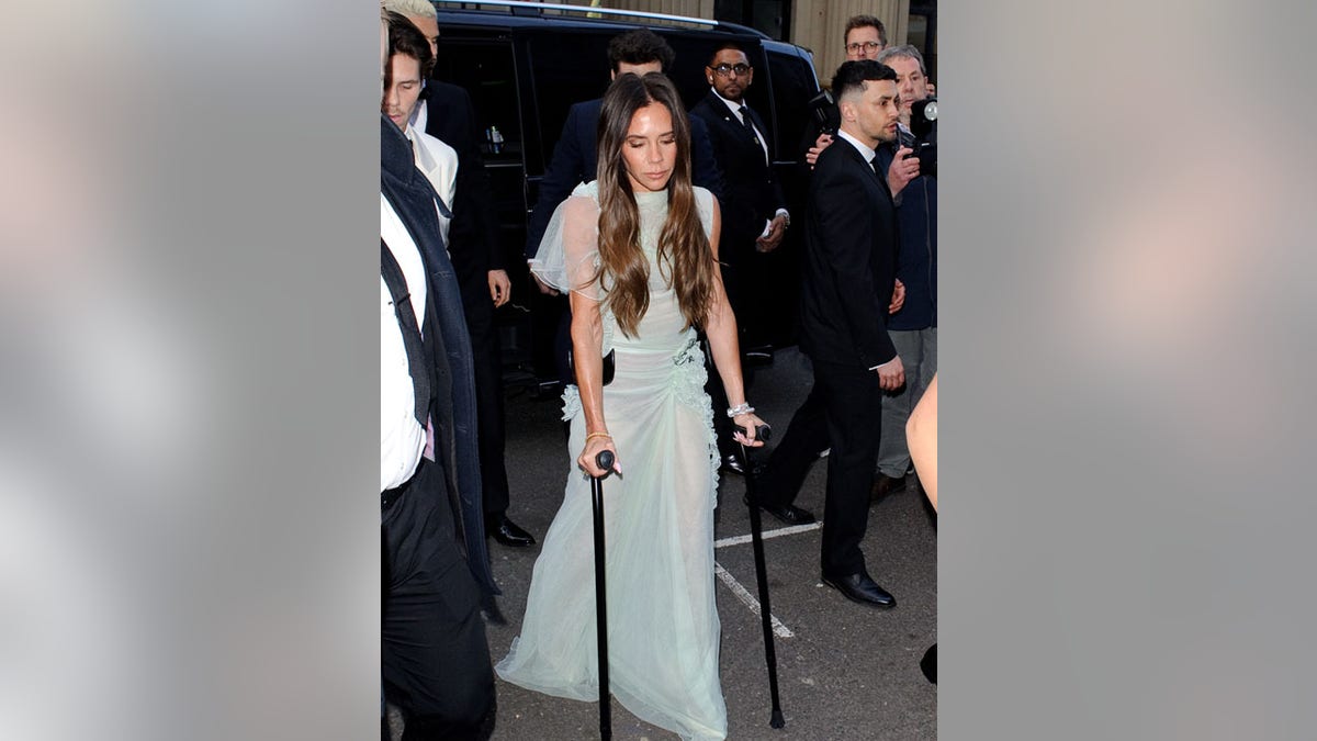 Victoria Beckham walking on crutches in a mint green gown