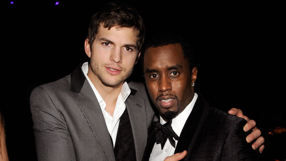 Sean Combs and Ashton Kutcher hug in suits