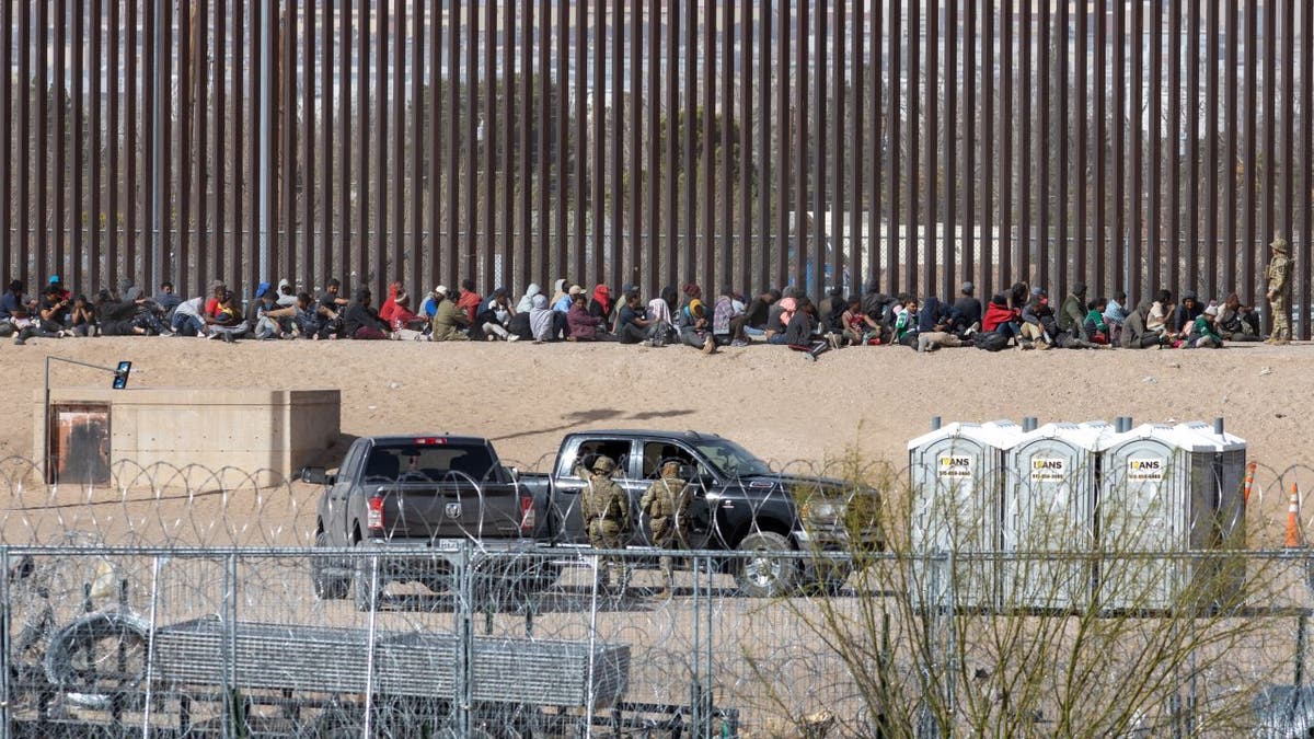 Migrants sitting adjacent separator wall
