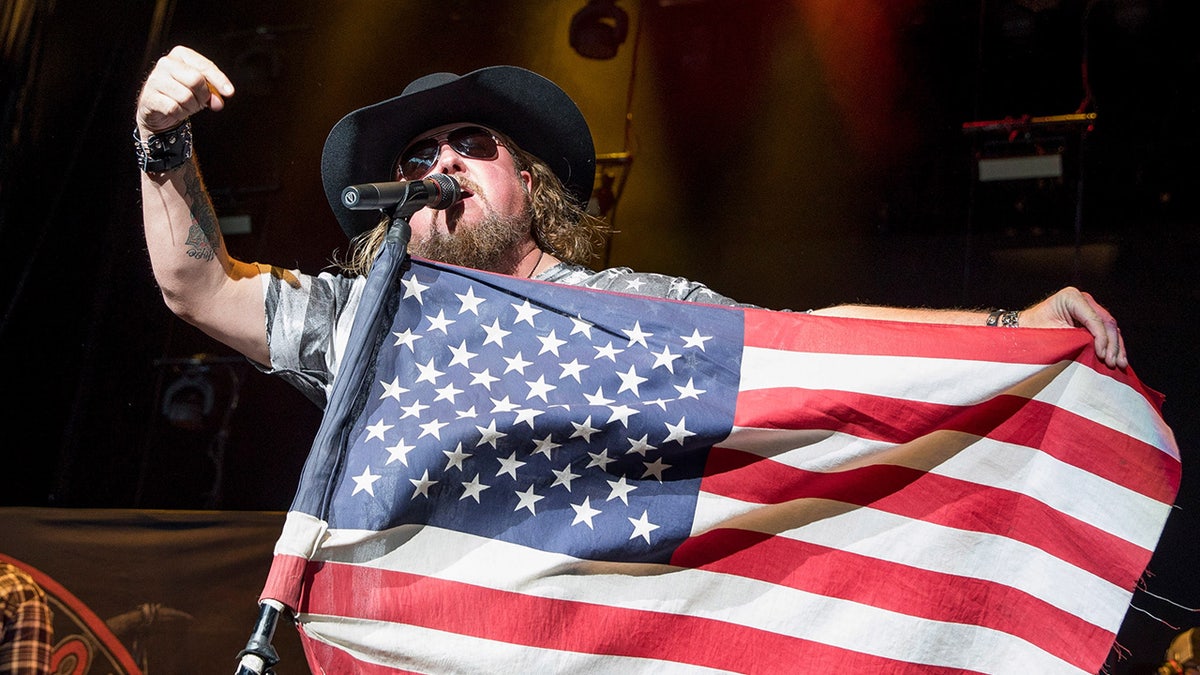 Country vocalist Colt Ford holds an American emblem astatine nan microphone
