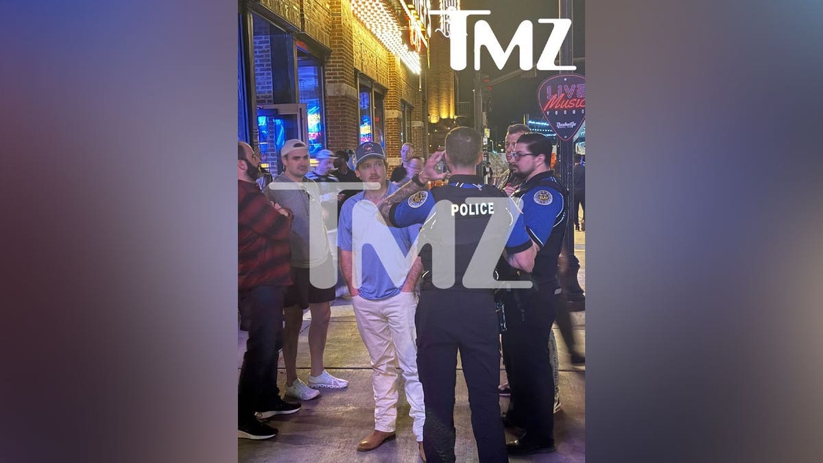 A photo of Morgan Wallen with police officers after throwing chair off roof