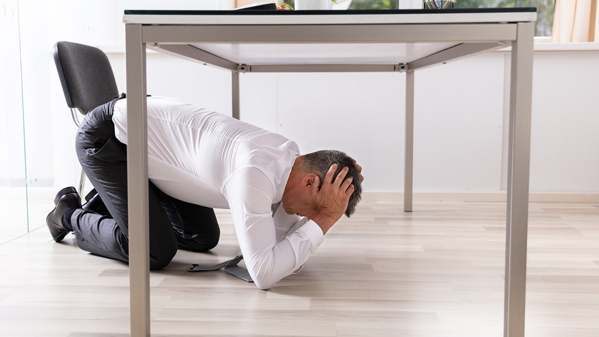 Man hiding under desk