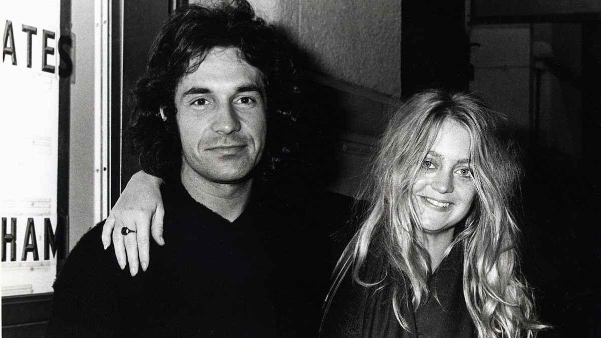 Black and white photo of Bill Hudson with wife Goldie Hawn with her arm around him
