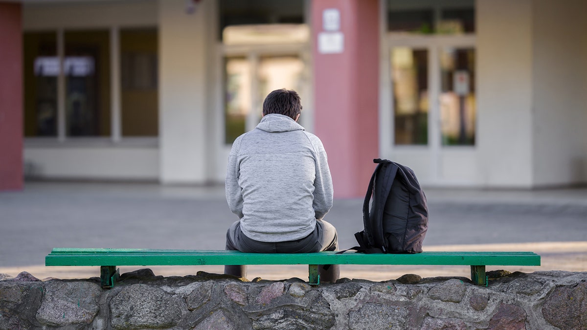 Seorang remaja laki-laki duduk sendirian di sekolah