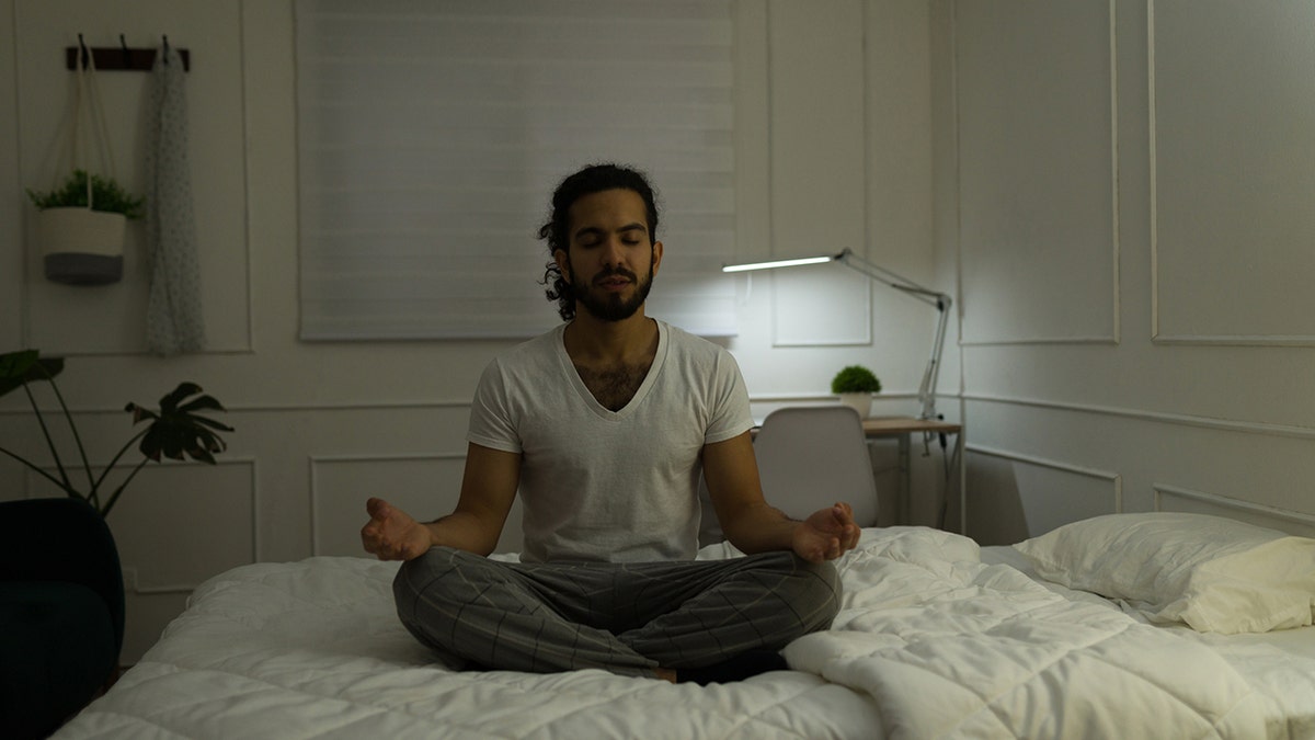 man meditates at night on his bed