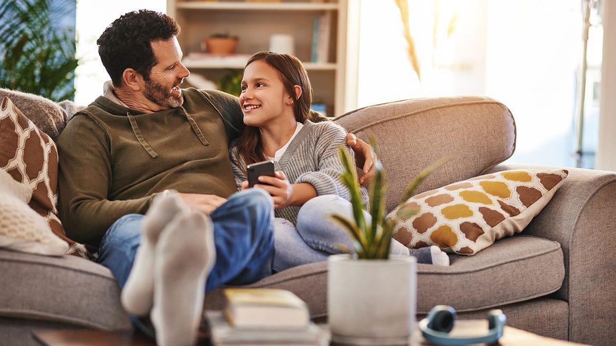 father and teen girl connected couch