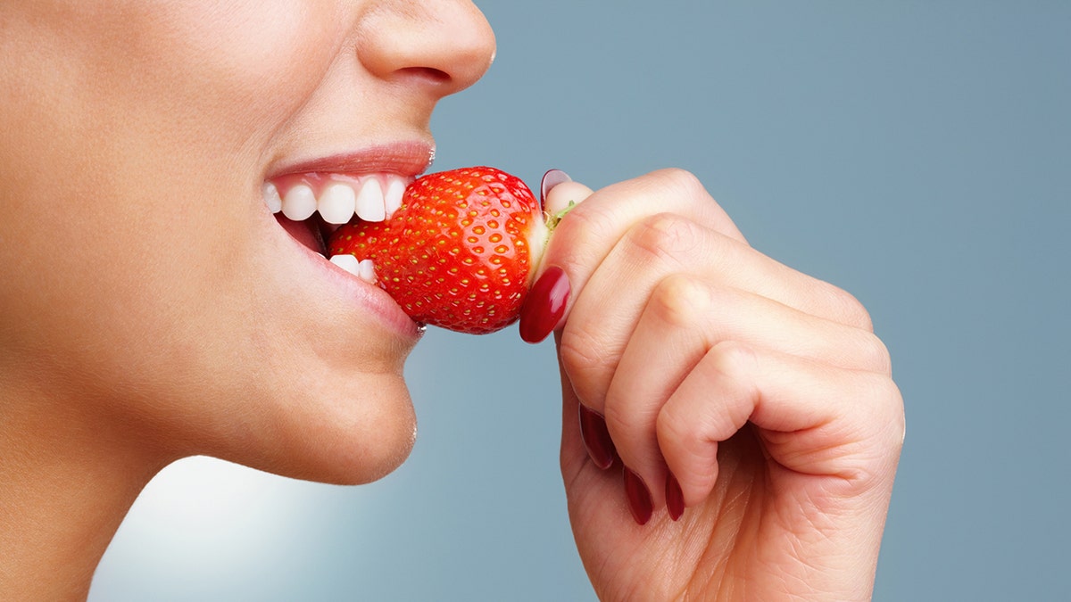 woman bites a strawberry