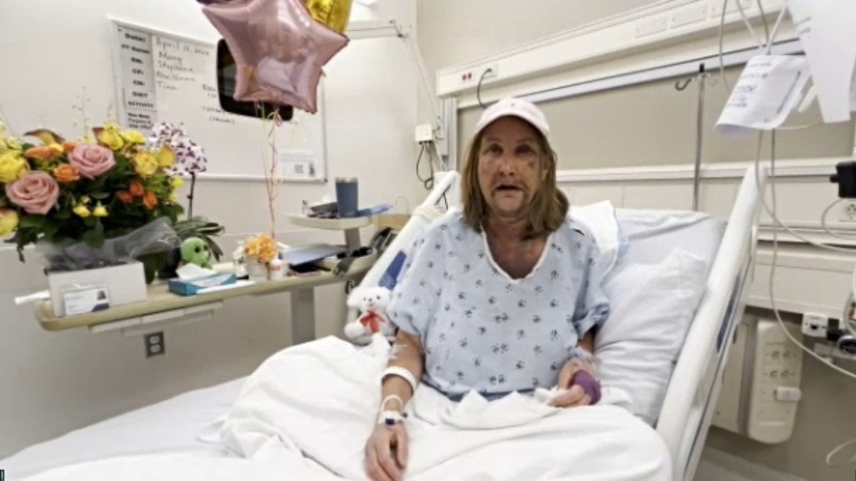 Mary Klein in a hospital bed with flowers next to her