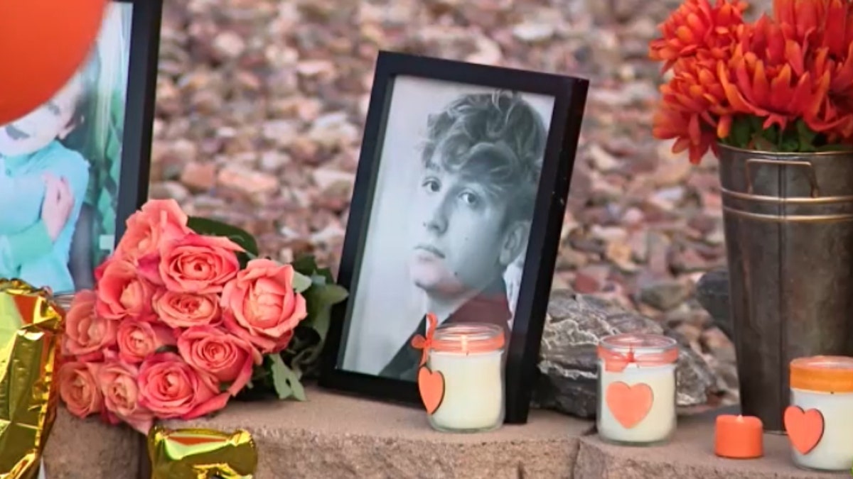 A framed photo of Preston Lord surrounded by candles and other mementos at a vigil