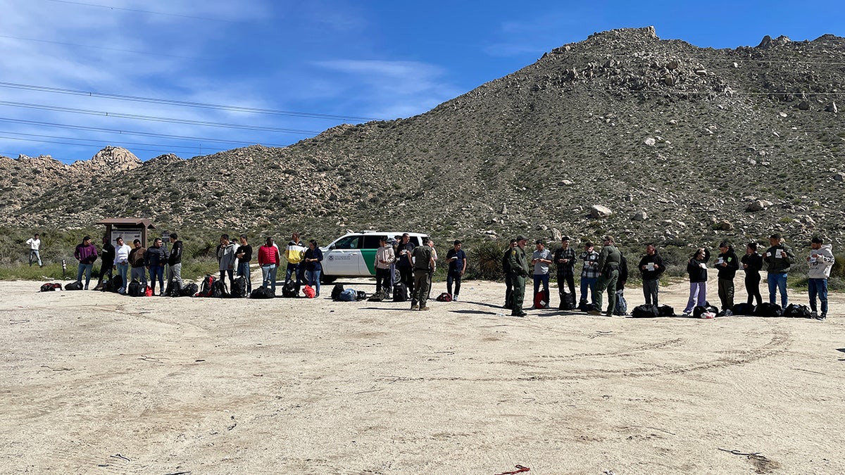 Around 30 migrants line up in dirt parking lot near California-Mexico border