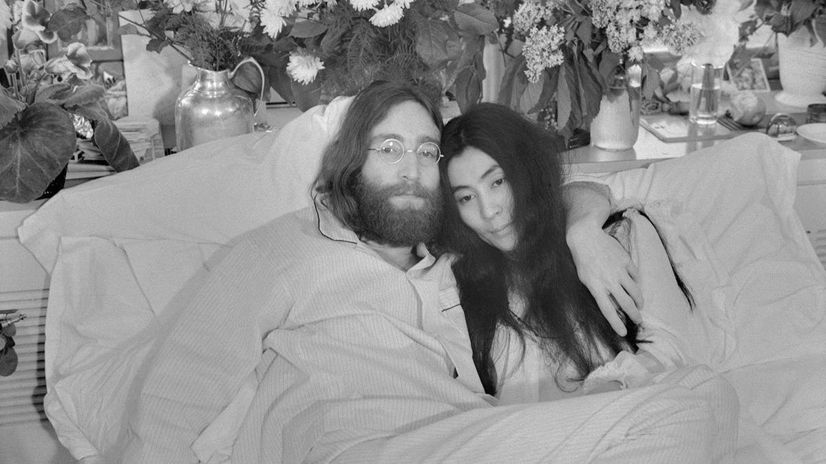 John Lennon e Yoko Ono posando na cama