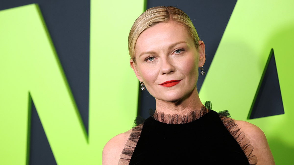Kirsten Dunst looks serious on the carpet in a black tulle dress