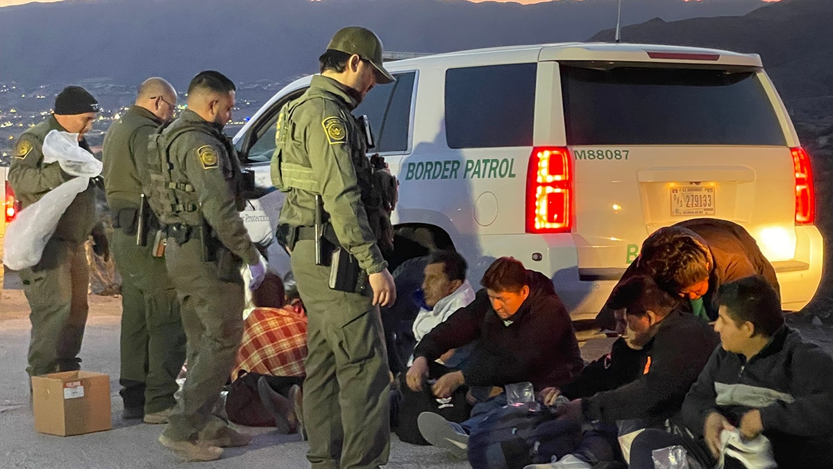 Border Patrol detaining migrants by white SUV