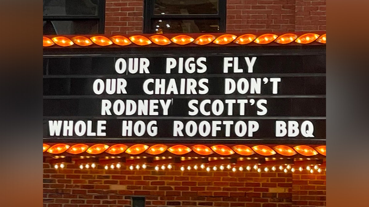 Sign that says "Our pigs fly our chairs dont rodney scotts whole hog rooftop bbq"
