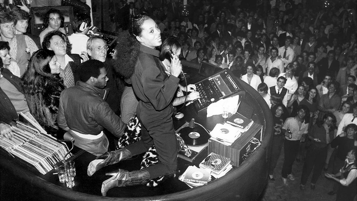 Black and white photo of Diana Ross with a crowd beneath her at Studio 54