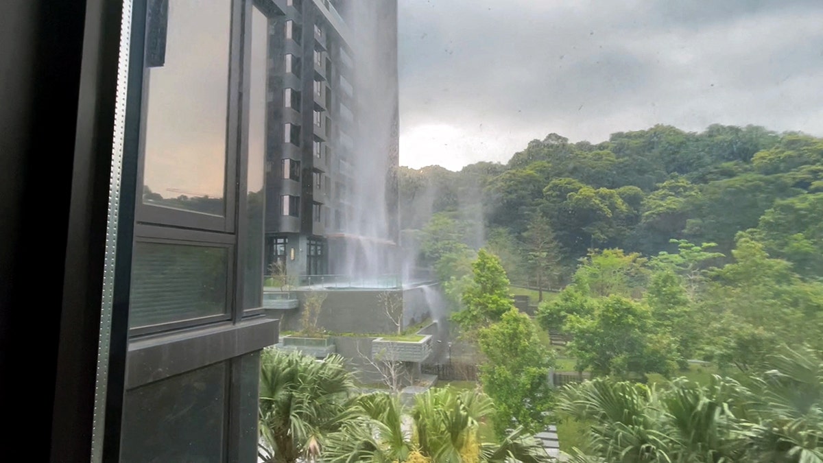 Debris falls from a building, as seen from a nearby window