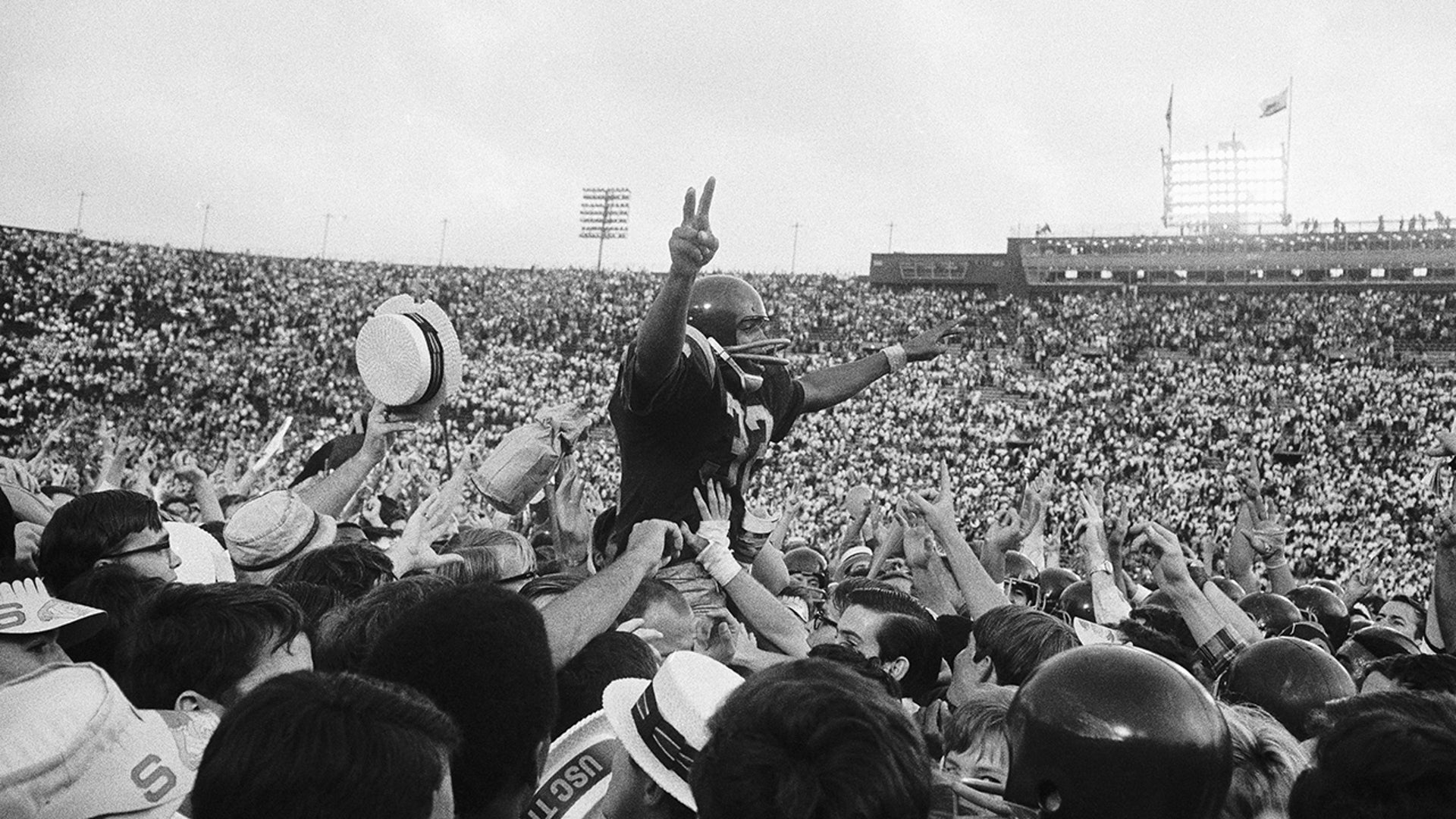 O.J. Simpson, USC's running back gives the victory sign as he is carried off the field by hundreds of cheering fans