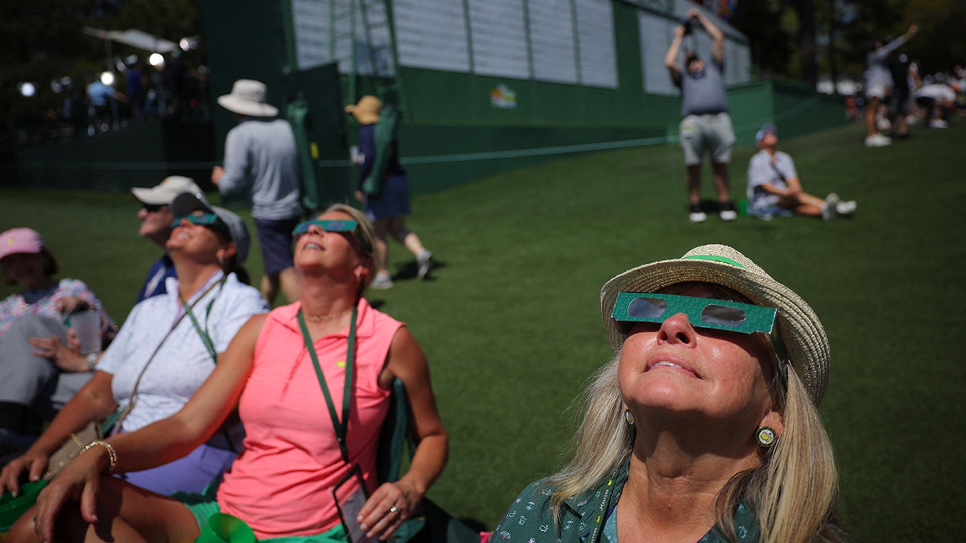 Viewers use special protective glasses to observe a total solar eclipse during a practice round at The Masters Golf Tournament