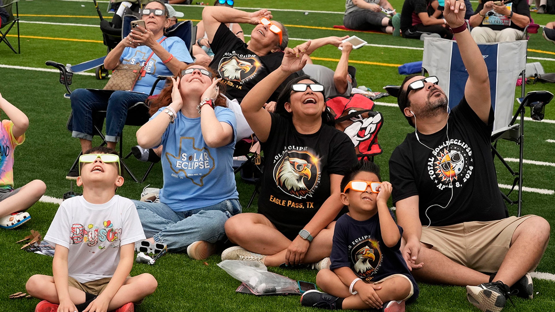 People watch as the moon partially covers the sun during a total solar eclipse