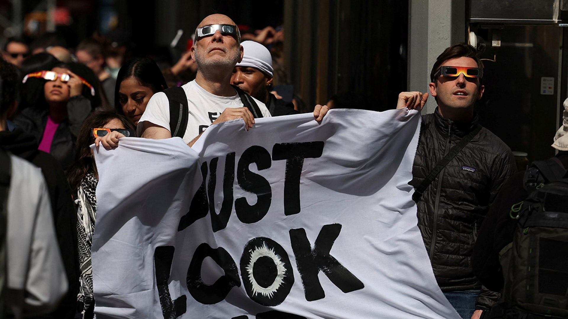 People assemble to view a partial solar eclipse,at Times Square in New York City