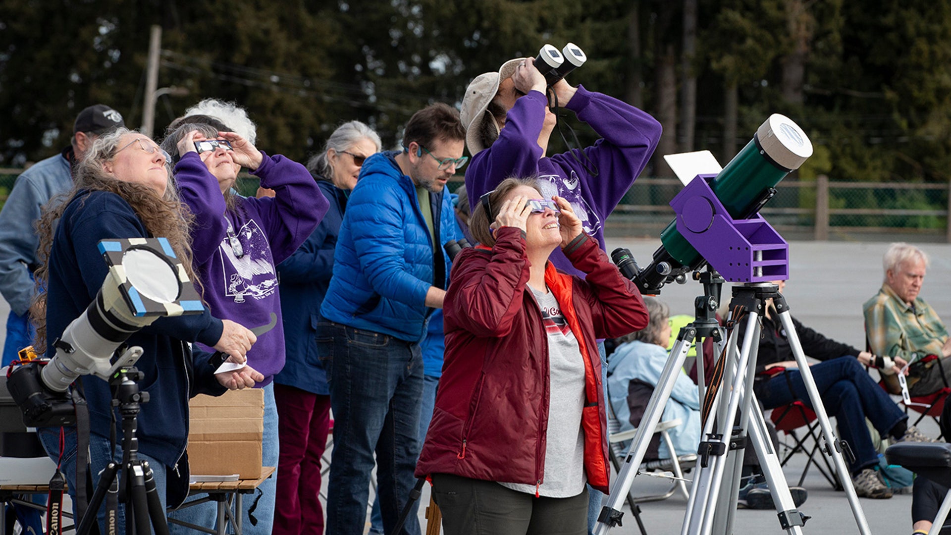 People watch as the moon begins to cover the sun during a partial solar eclipse at the College Hill Reservoir in Eugene, Oregon
