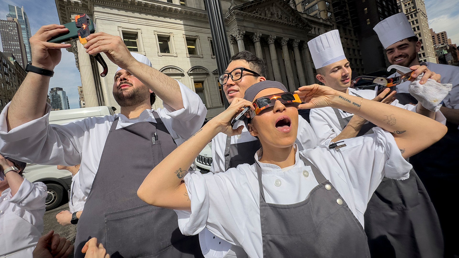 Restaurant workers in the Flatiron district of Manhattan take a break to view the solar eclipse