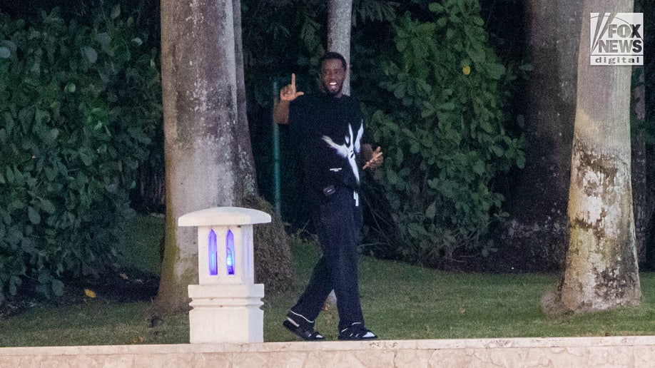 Sean "Diddy" Combs signals to boaters as they pass by his Star Island home in Miami Beach, Florida