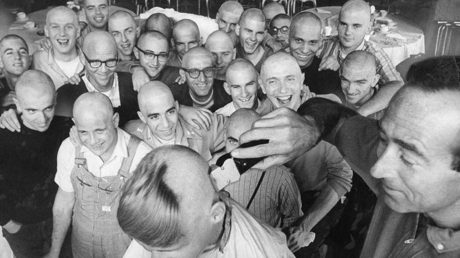 Members of Synanon have their head shaved to perform as extras in a movie. Dan Sorkin is doing the shaving.