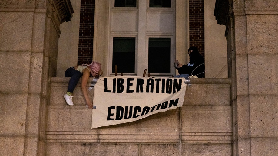 Manifestantes del campamento pro Palestina en el Campus de Columbia muestran una pancarta mientras se atrincheran en Hamilton Hall