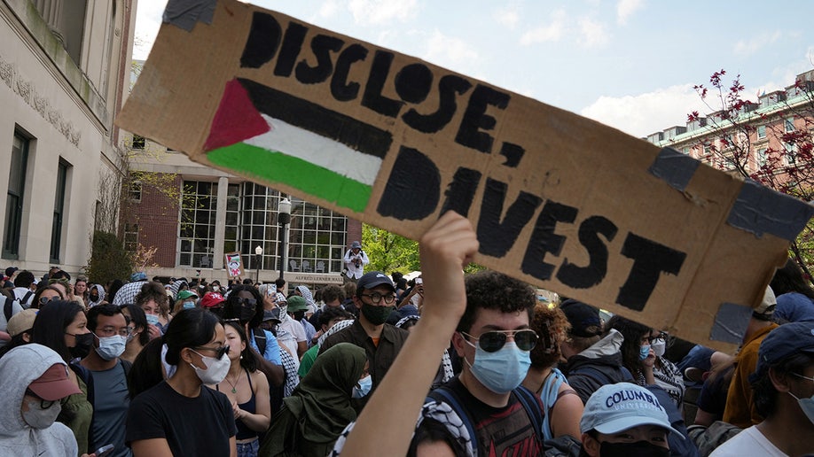 Un manifestante sostiene un cartel durante una marcha en el campus de la Universidad de Columbia en apoyo de un campamento de protesta en favor de los palestinos