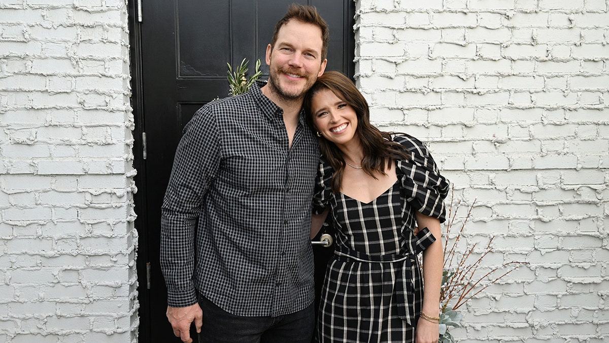 Chris Pratt in a black and white checkered shirt smiles with Katherine Schwarzenegger in a black and white plaid dress