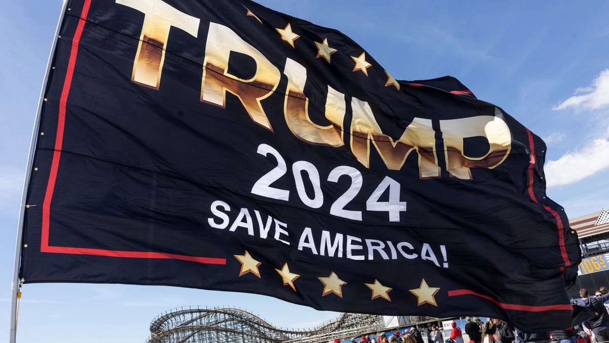 A Trump 2024 flag flutters in the wind during a rally