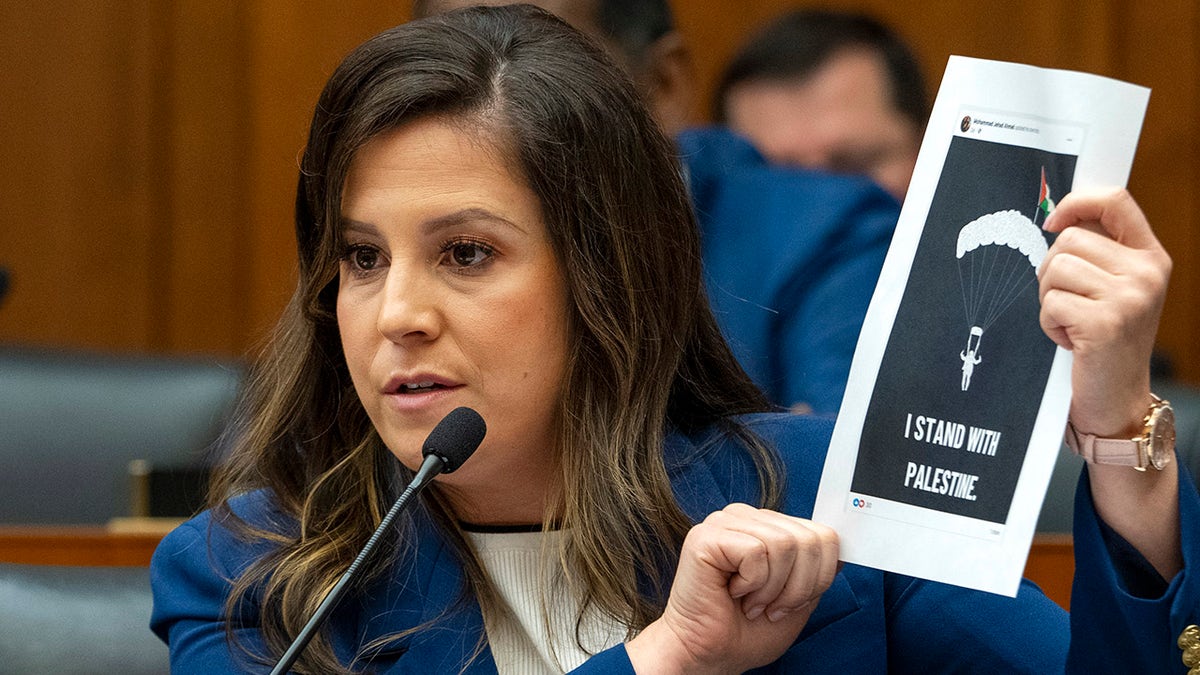 Stefanik holds up   photograph  of Hamas paraglider posted by NYC teacher