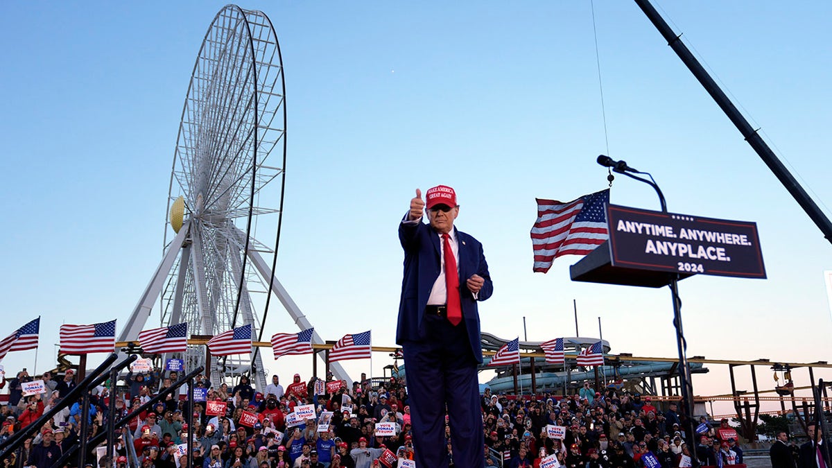 President Trump points to the rally as a Ferris wheel, with the American flag visible in the background