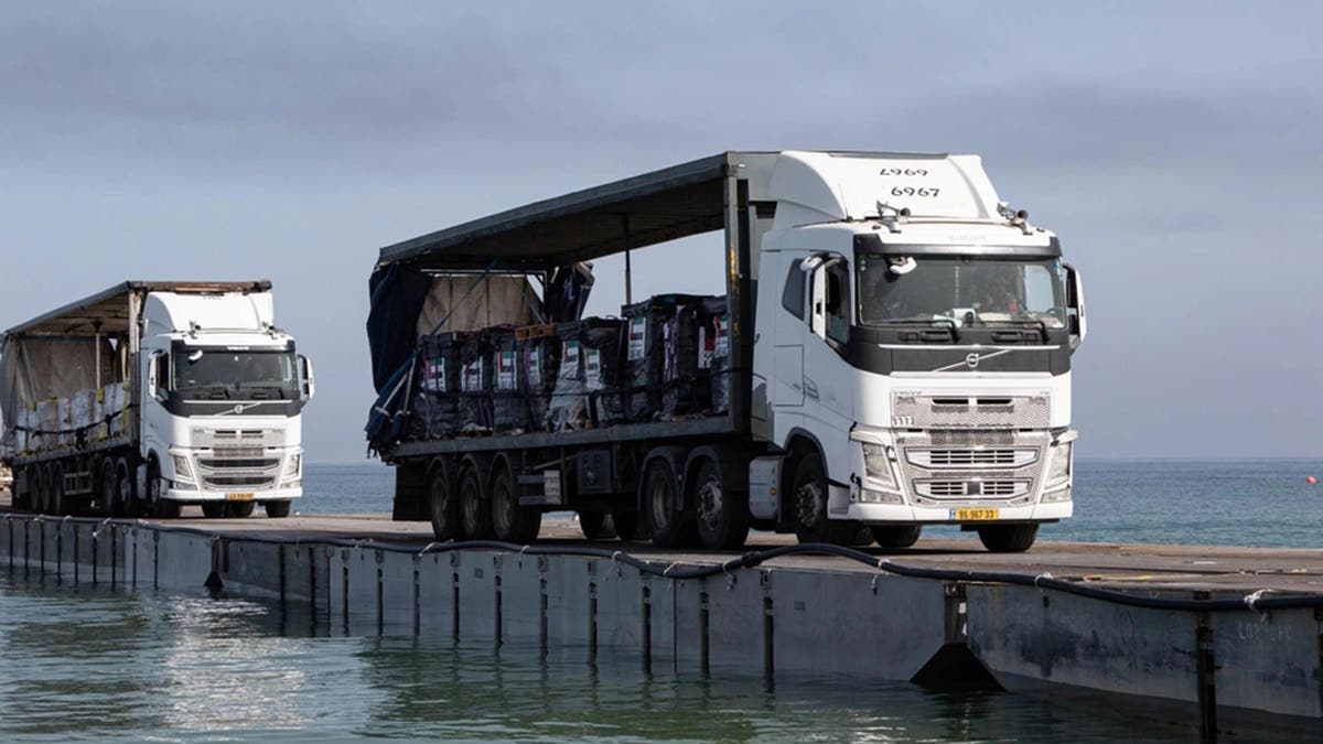 Trucks loaded with humanitarian aid from the United Arab Emirates and the United States Agency for International Development cross the Trident Pier before entering the beach in Gaza, May 17, 2024. The Pier has since been damaged by choppy seas.