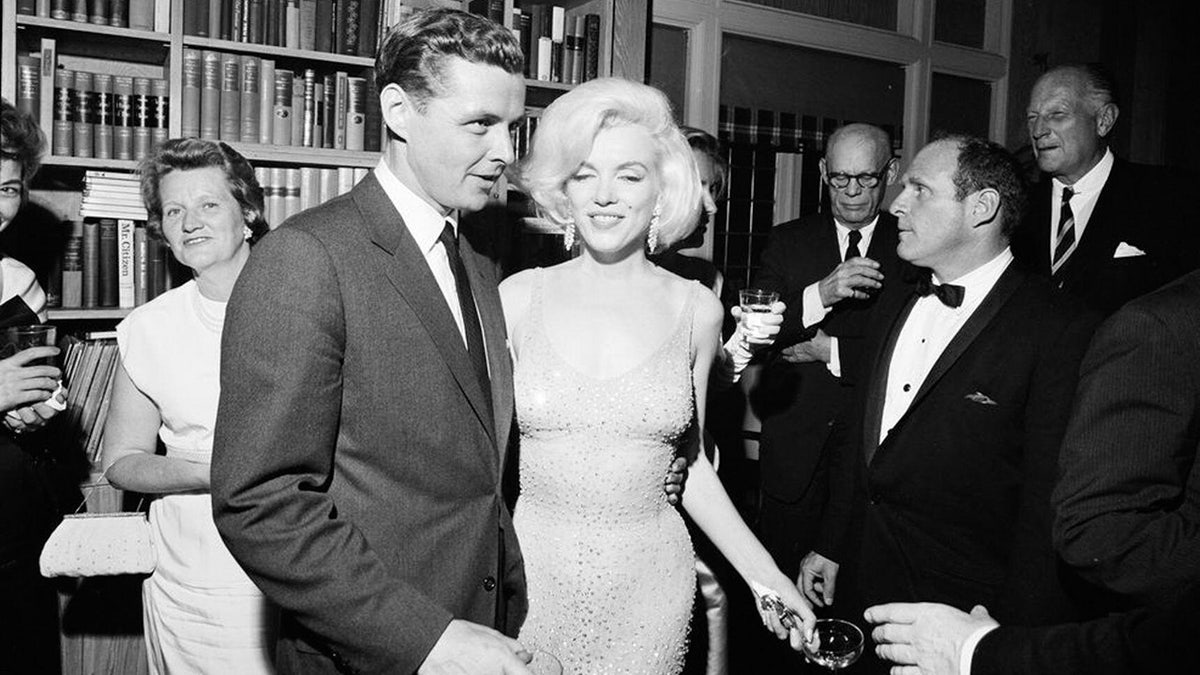 Marilyn Monroe walking next to a man in a suit