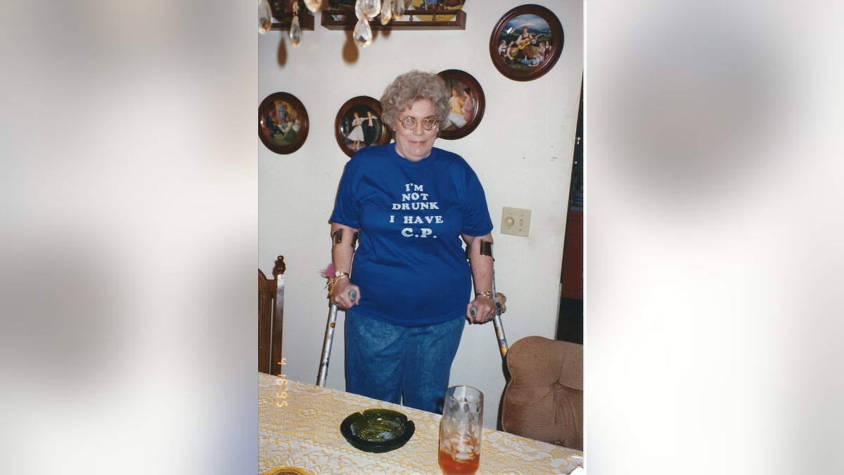 Barbara Mabee Abels sister wearing a blue shirt and jeans and holding onto crutches