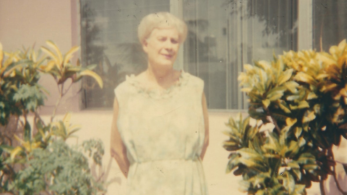 Barbara Mabee Abels mother standing in between plants outside her home