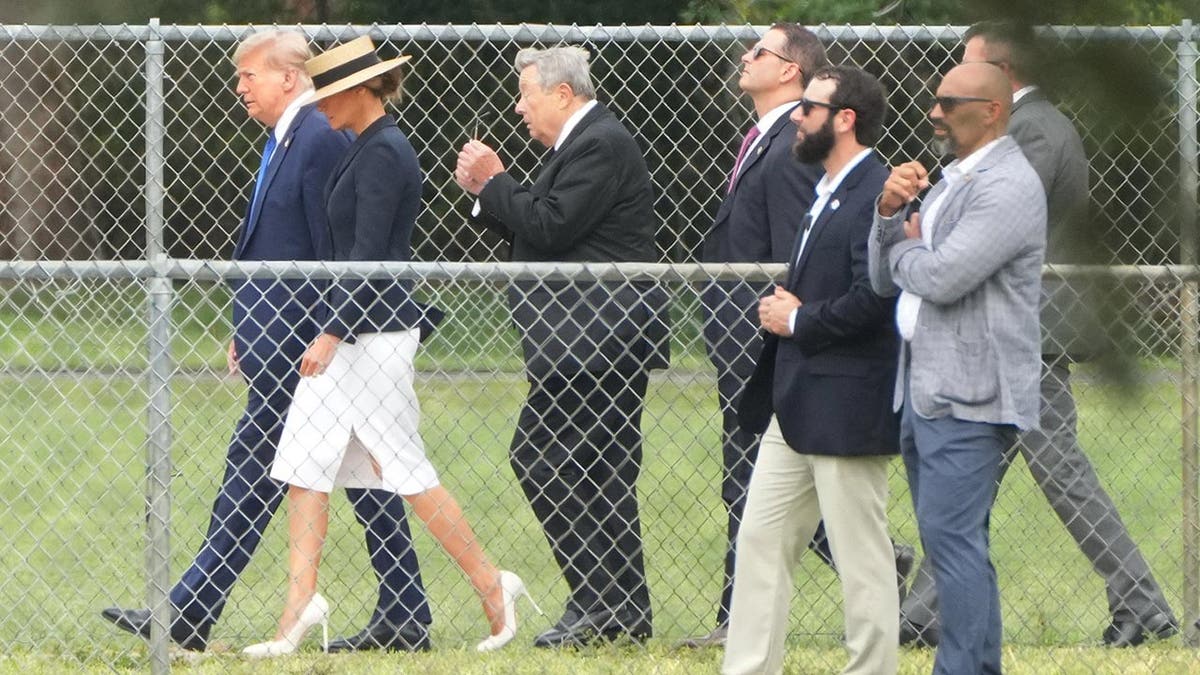 The Trump family walks past a fenced property